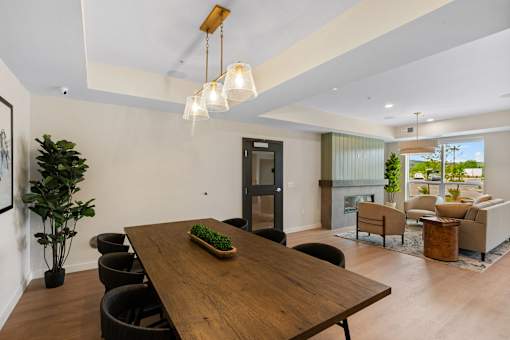 A long wooden table with a green plant on it is in the middle of a room with a black door at The Beaumont Apartments, Bozeman
