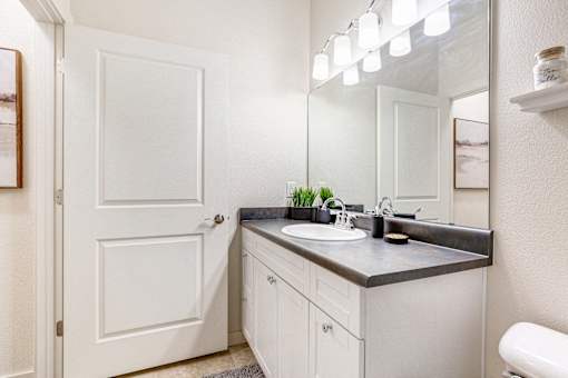 a bathroom with a sink and a mirror and a door at Corso Apartments, Missoula, MT