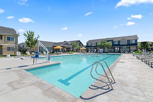 A swimming pool with a diving board and a person sitting on a chair.