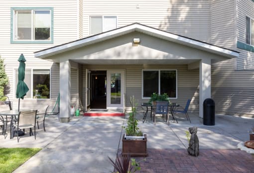 a patio with tables and chairs and a dog in front of a house