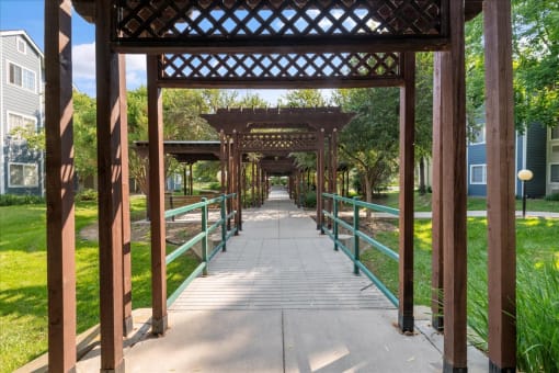 a covered walkway with a bridge over a river