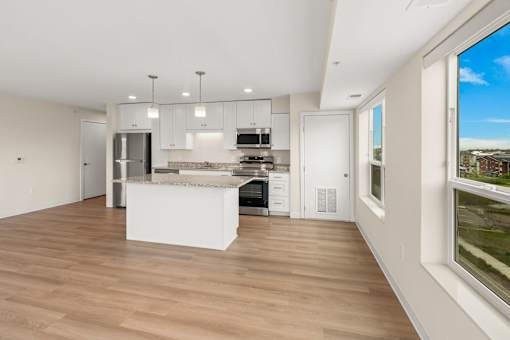 A modern kitchen with a white island and wooden floors at The Beaumont Apartments, MT 59715