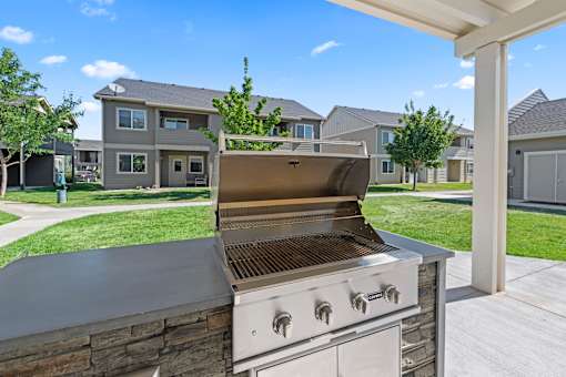 A modern outdoor kitchen with a grill and a stone countertop.