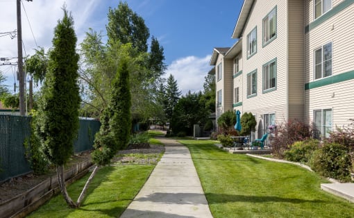 a walkway between two apartment buildings with grass and trees