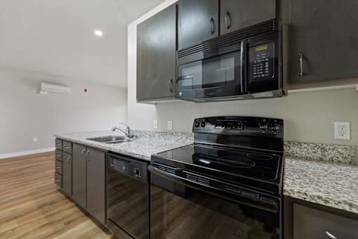 A black microwave is mounted above a black stove in a kitchen.