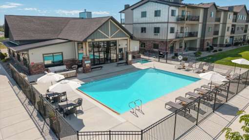 A large swimming pool surrounded by a black fence and lounge chairs.