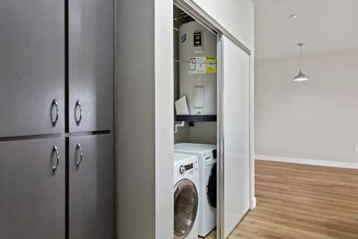 A washing machine is in a small alcove in a room.
