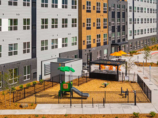 A playground with a green slide and a yellow umbrella at The Beaumont Apartments, Bozeman, Montana 59715