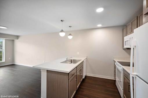 A kitchen with white appliances and brown cabinets.