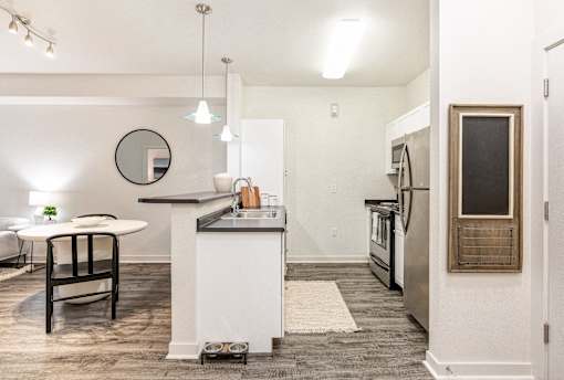 a living room with a kitchen and a dining area with a table and chairs at Corso Apartments, Missoula, MT