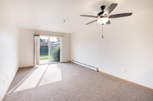 an empty living room with a ceiling fan and a sliding glass door