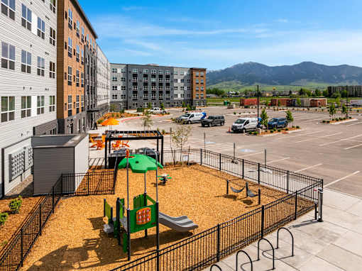 A playground with a green slide and a red sign at The Beaumont Apartments, Bozeman