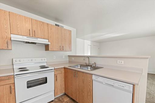 A kitchen with a white stove top oven and a white dishwasher.