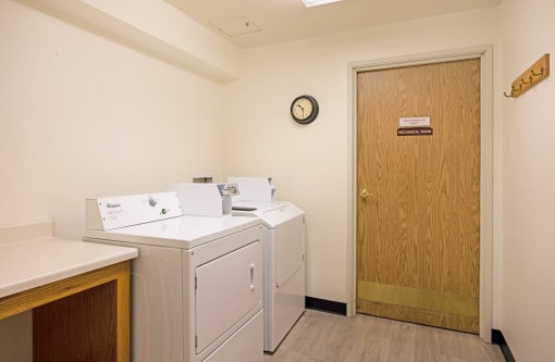 a laundry room with washers and dryers and a door to a room with