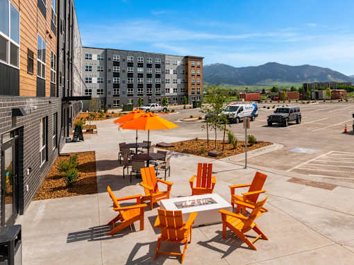 A patio with orange chairs and a table with a white tablecloth at The Beaumont Apartments, Montana, 59715