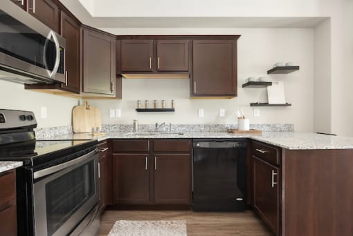 a kitchen with dark cabinets and granite counter tops at The Alloy at Geneva, Vineyard, Utah