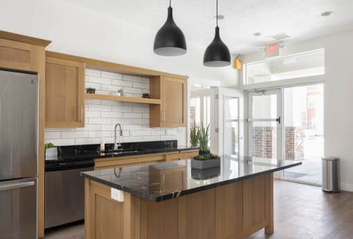 a kitchen with wooden cabinets and a large island with a black countertop at The Alloy at Geneva, Vineyard, 84058