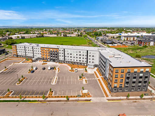 A large multi-story building with a parking lot in front at The Beaumont Apartments, Montana