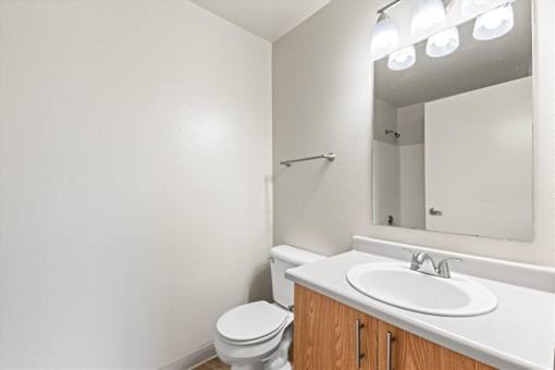 A white bathroom with a toilet, sink, and mirror.