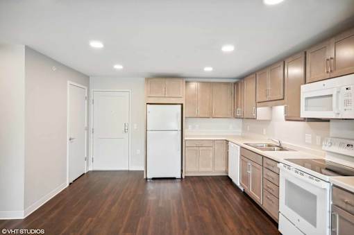 A kitchen with white appliances and wooden cabinets.