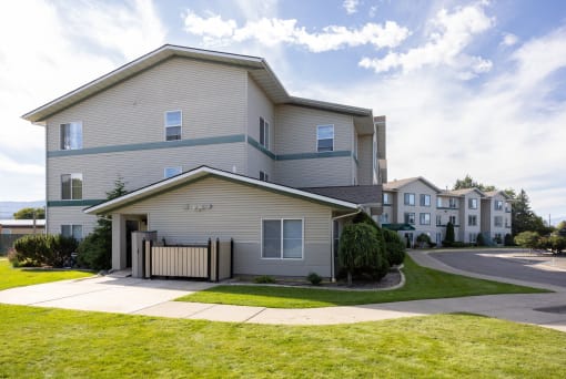 the view of an apartment building with a sidewalk and grass