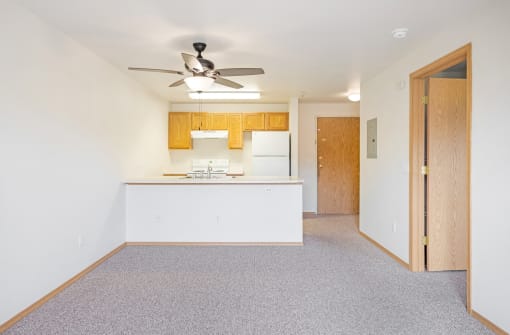 a room with a kitchen and a ceiling fan