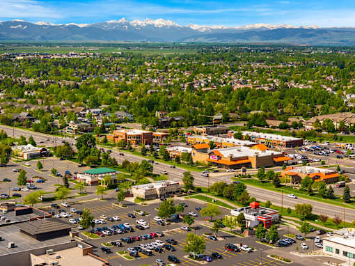 A parking lot with cars and a mountain range in the background at The Beaumont Apartments, Bozeman, 59715