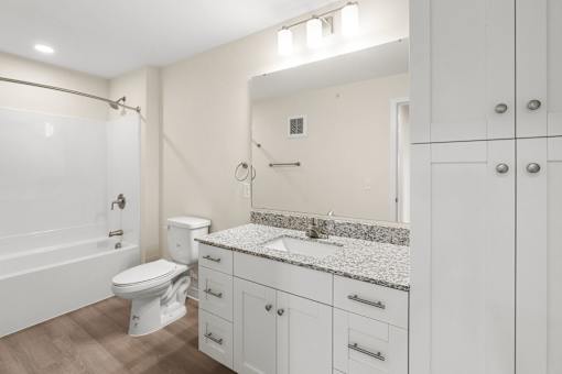 A white bathroom with a toilet, sink, and mirror at The Beaumont Apartments, Bozeman, 59715