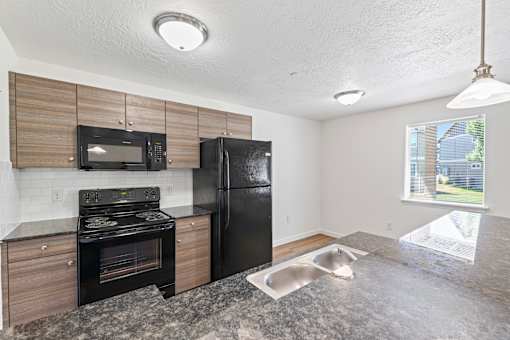 A kitchen with black appliances and a marble countertop.