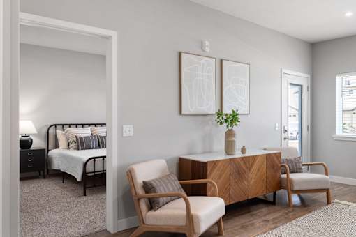 A bedroom with a bed, chair, and two pictures on the wall.