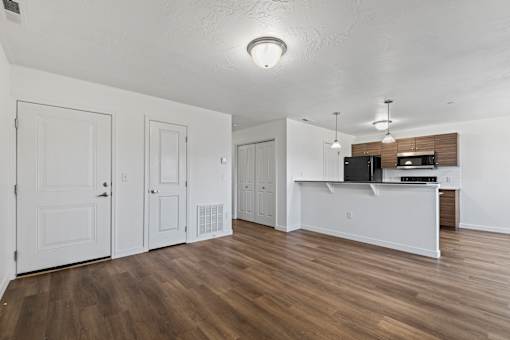 A kitchen area with white cabinets and a wooden floor.