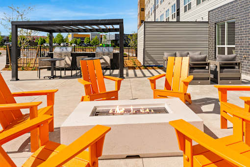 A patio with orange chairs and a fire pit at The Beaumont Apartments, Bozeman, Montana 59715