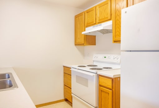a kitchen with white appliances and wooden cabinets and a refrigerator