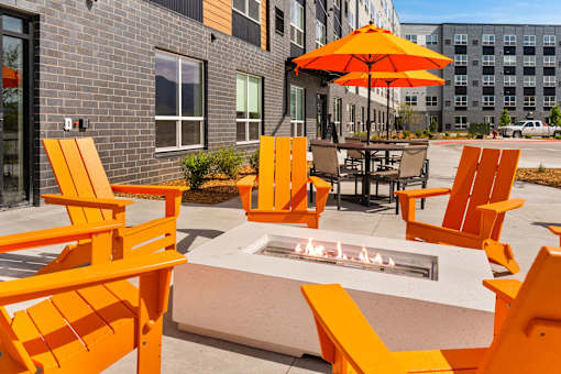 A patio with orange chairs and a fire pit at The Beaumont Apartments, Bozeman, MT
