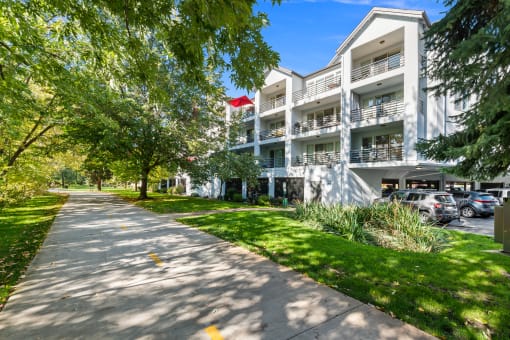 a sidewalk in front of a white apartment building with trees and grass at River Walk Apartments, Boise, 83702