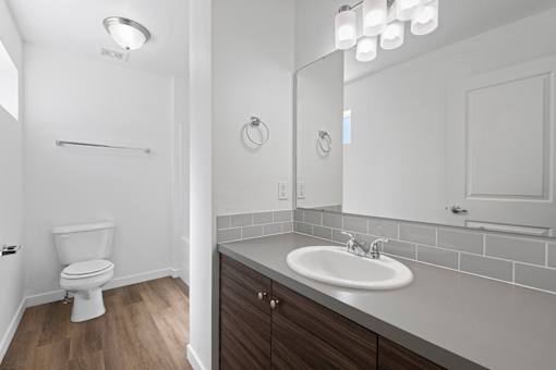 A white toilet is in a small bathroom with a white sink.