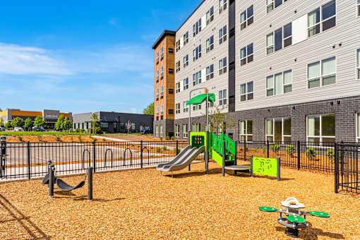 A playground with a green slide and a yellow sign at The Beaumont Apartments, Bozeman, 59715