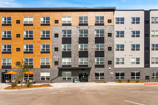 A large multi-story building with a black entrance and a tree in front at The Beaumont Apartments, MT 59715