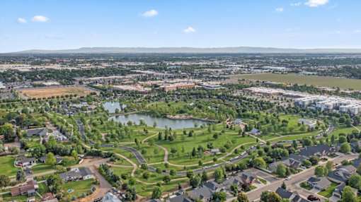A bird's eye view of a residential area with a lake and greenery. at Verraso Village Apartments, Meridian, ID, 83646