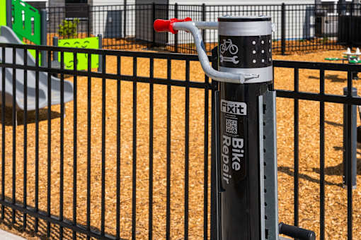 A black fence with a bike repair station in front of it at The Beaumont Apartments, Bozeman