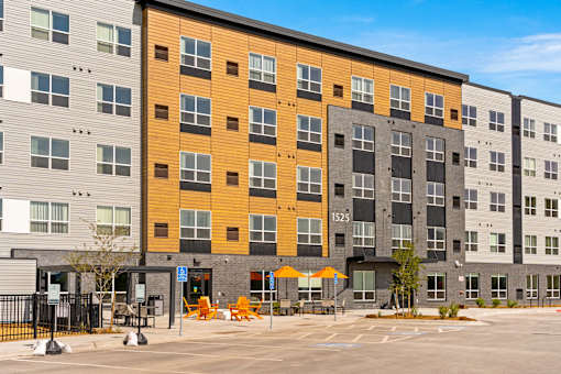 A modern apartment building with a parking lot in front at The Beaumont Apartments, Bozeman