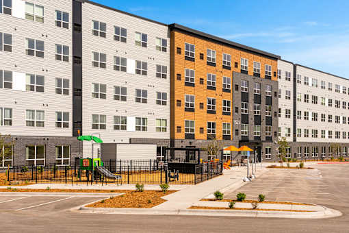 A modern apartment complex with a playground in front at The Beaumont Apartments, Montana