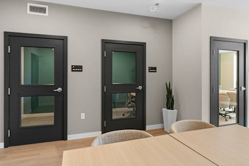 Three black doors with glass panels are in a room with a wooden table and chairs at The Beaumont Apartments, Bozeman