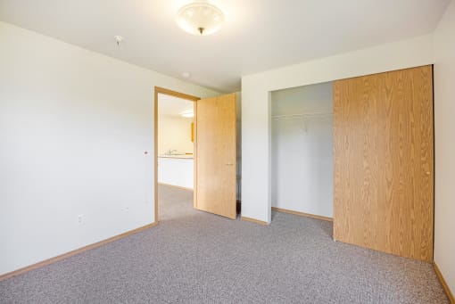 an empty room with a door to a closet and a mirror