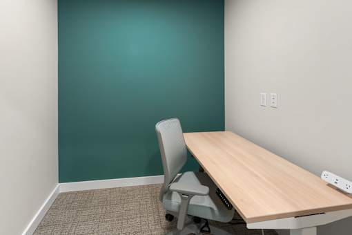 A room with a green wall and a wooden table with a grey chair at The Beaumont Apartments, Bozeman, MT