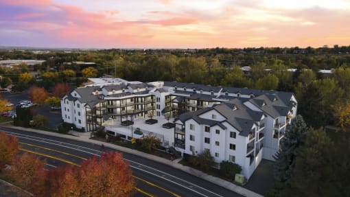 an aerial view of a white and gray apartment building with a sunset in the background at River Walk Apartments, Boise, ID
