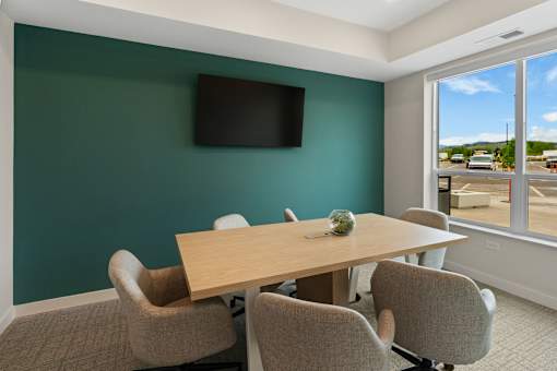 A conference room with a table and chairs and a television on the wall at The Beaumont Apartments, Bozeman, Montana 59715