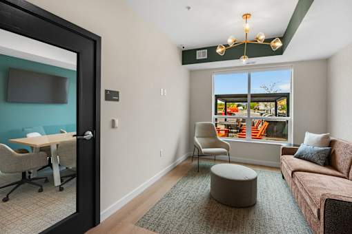 A room with a couch, chair, and table with a view of the outside at The Beaumont Apartments, MT 59715