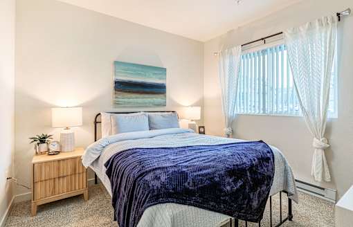 a bedroom with a bed and a window with white curtains at Corso Apartments, Missoula, MT
