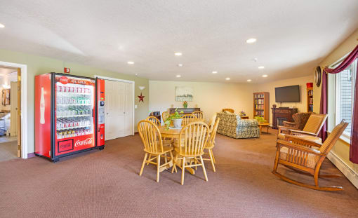 a living room with a table and chairs and a refrigerator